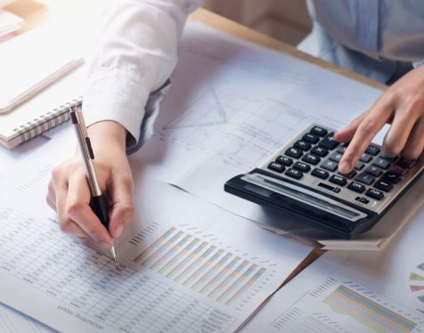 finance and accounting concept. business woman working on desk using calculator to calculate in office